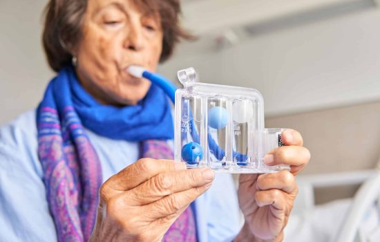 Woman using spirometer for respiratory therapy