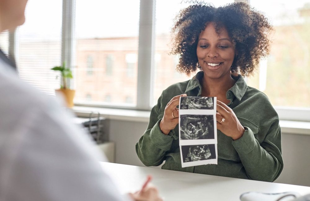 pregnant woman holding sonogram pictures smiling